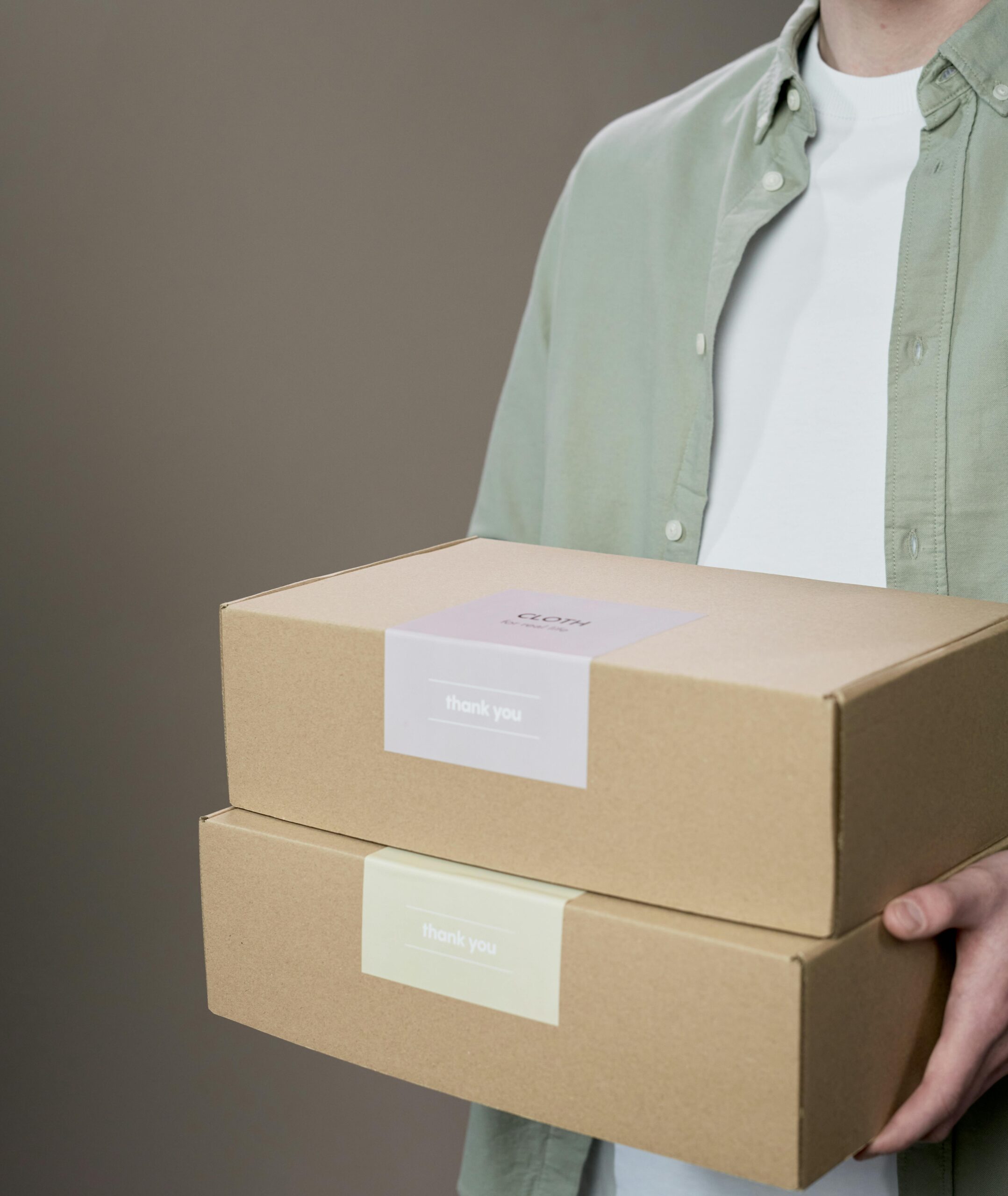 A person holding two labeled cardboard boxes against a neutral background.